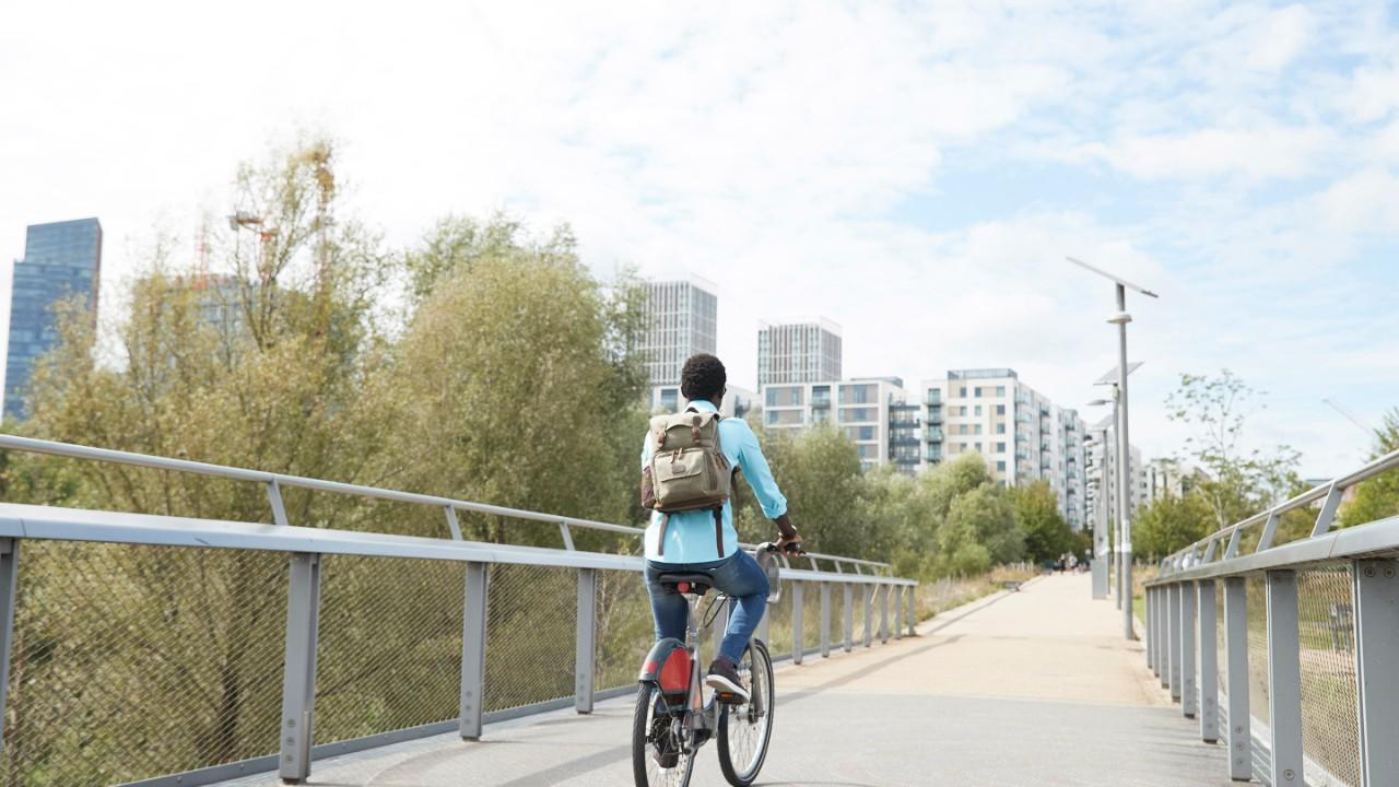 女孩在桥上骑自行车去城市.